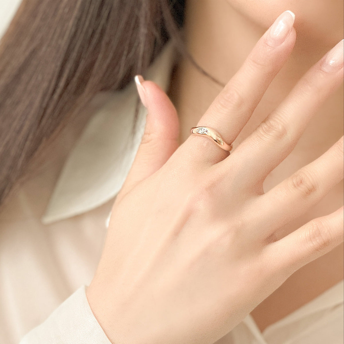 Close-up of a hand wearing a gold ring with a soft focus background