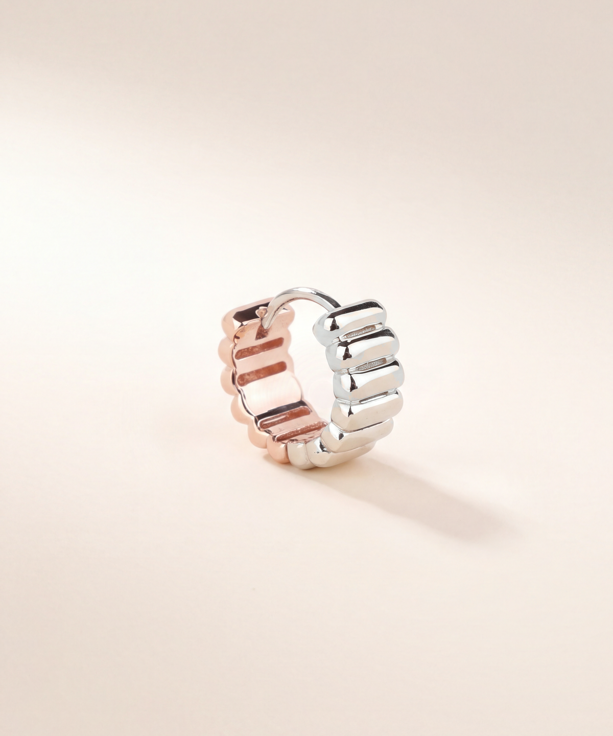Two-tone ribbed huggie hoop, single earring, white gold with rose gold, studio shot